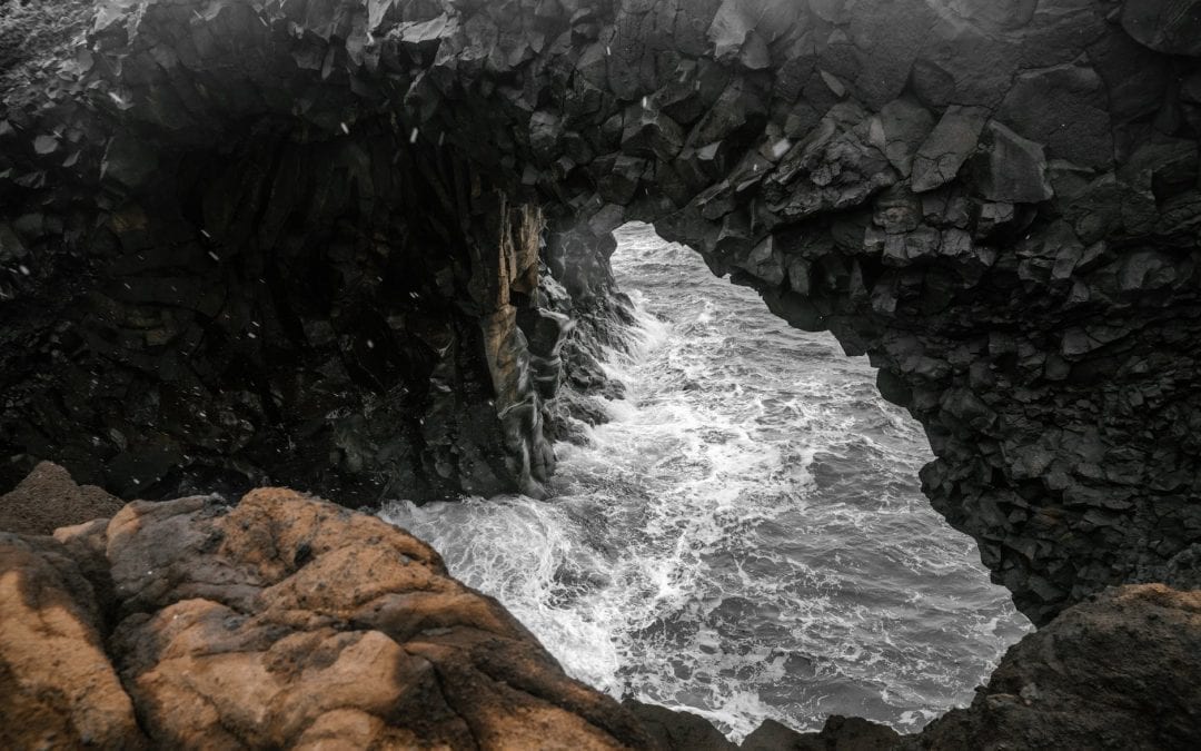 A teenage girl climbing a rock cliff with a man below her