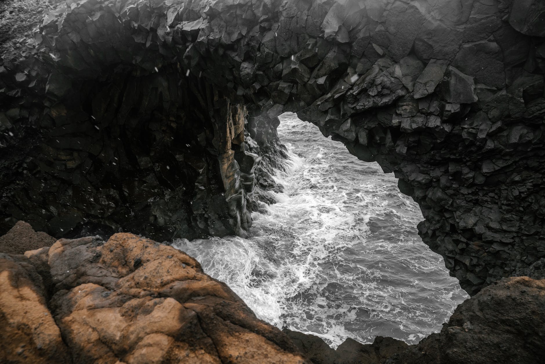 A teenage girl climbing a rock cliff with a man below her